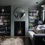 Cozy living room with a wood-burning stove, circular mirror, and bookshelves on both sides.