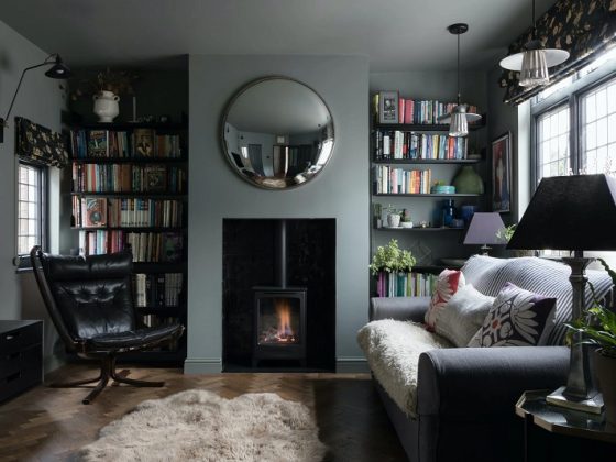Cozy living room with a wood-burning stove, circular mirror, and bookshelves on both sides.